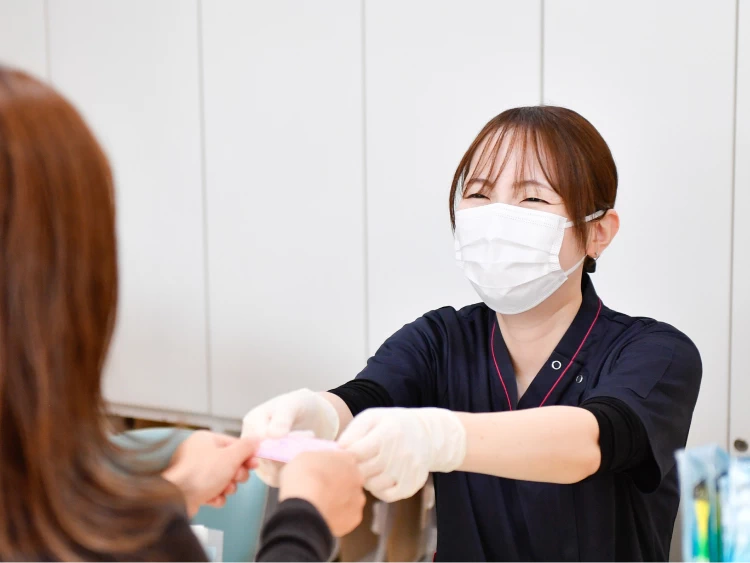 笑顔で診察券を受け渡しする受付スタッフ